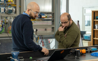 Two employees discussing programming of a new robot manufacturing cell